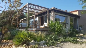 Pergola murale en pin lamellé-collé classe 4 adossée à la façade d'une maison contemporaine