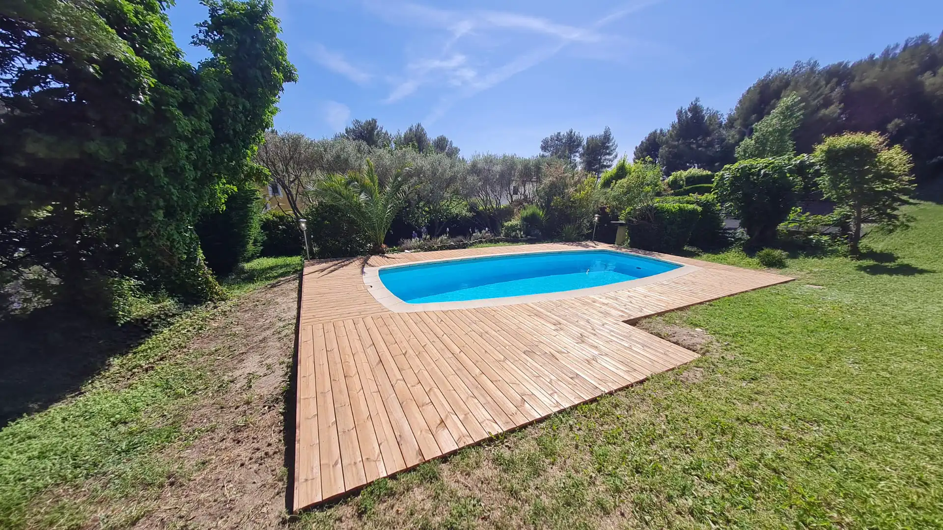 terrasse en bois autour d’une piscine enterrée avec jardin paysager et végétation méditerranéenne