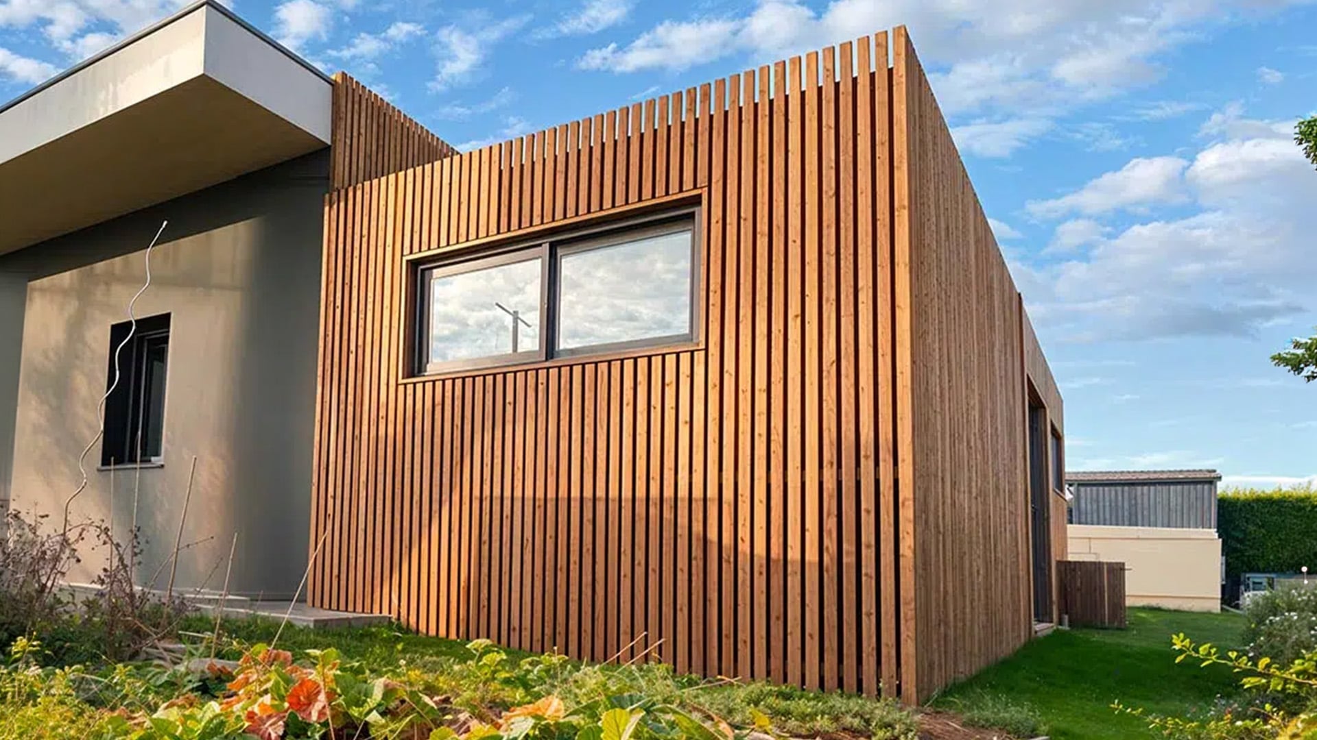 Façade en bardage Douglas et terrasse en bois rénovées avec une finition chaleureuse, protégées contre le vieillissement extérieur.