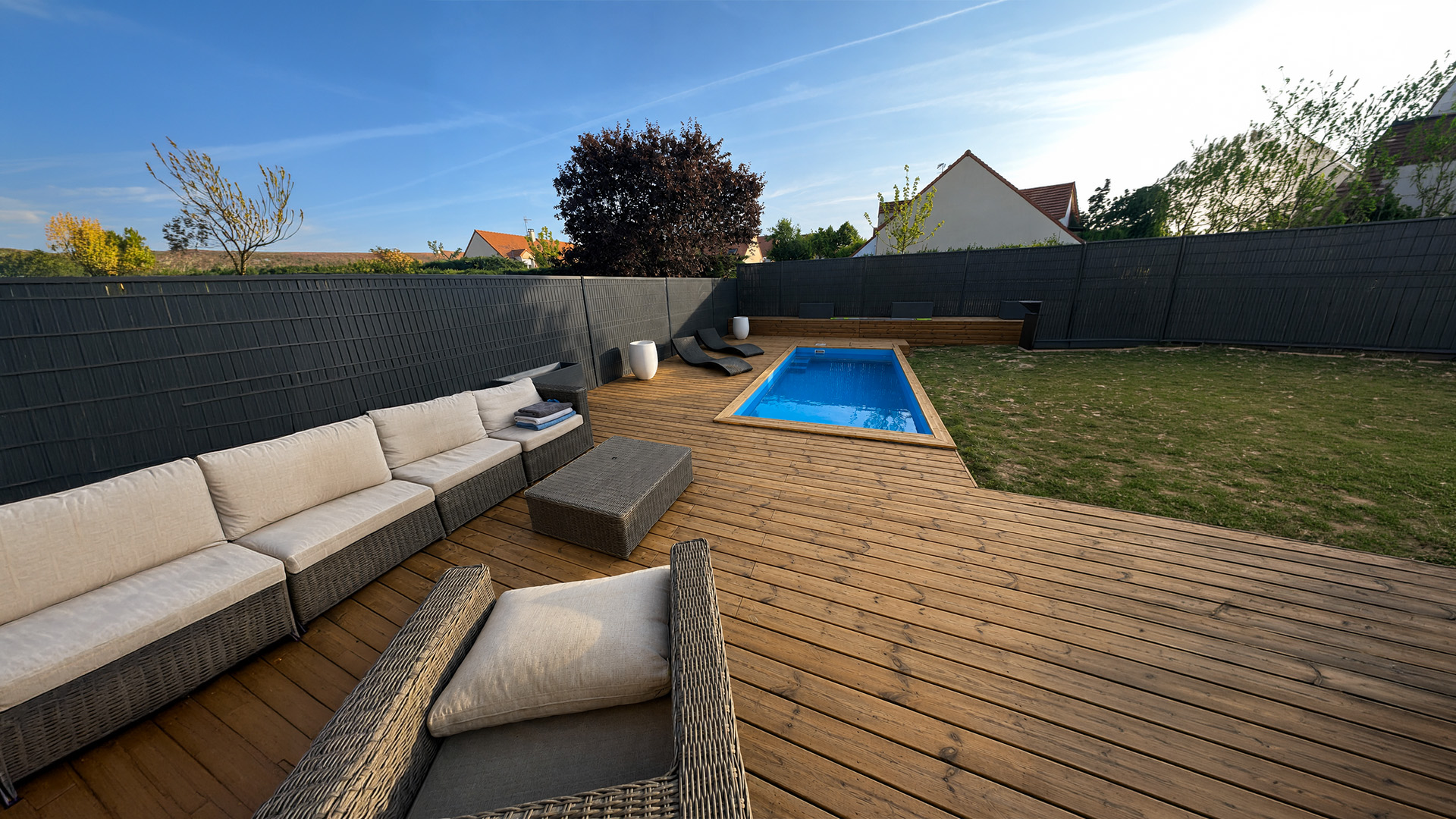 Grande terrasse en bois extérieur protégée et entretenue, aménagée autour d’une piscine avec mobilier de jardin et espace détente.