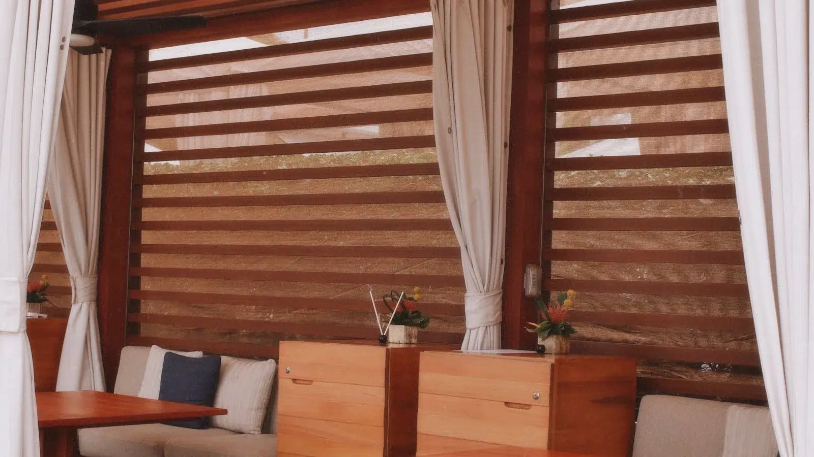 Pergola bois fermée par des rideaux extérieurs en toile imperméable pour profiter de la terrasse en 4 saisons