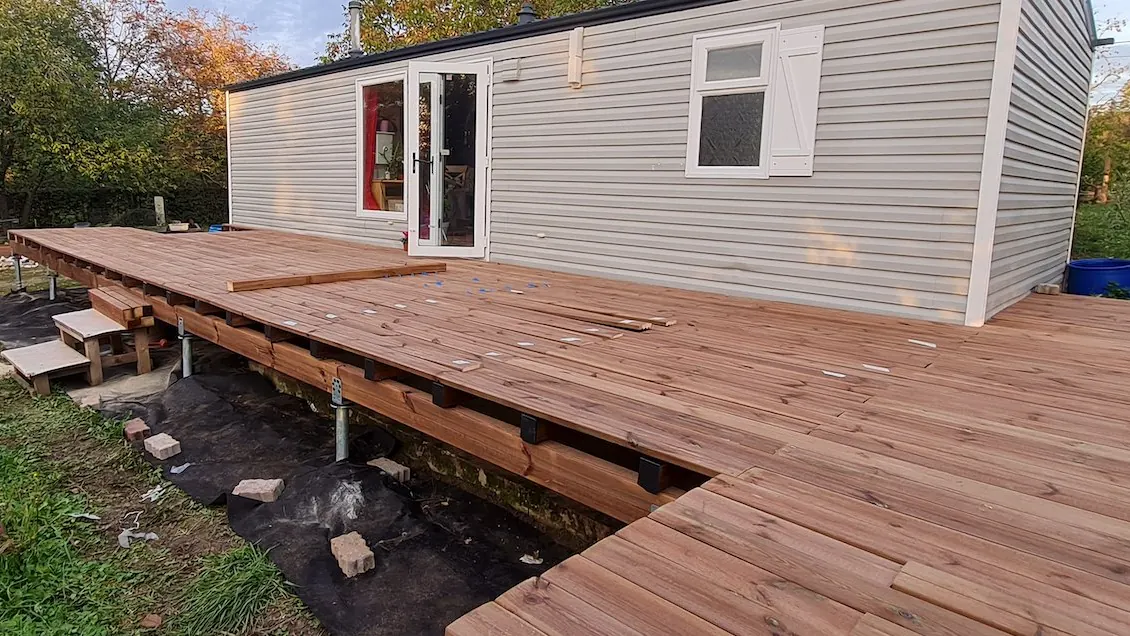 Terrasse bois sur pilotis : guide complet (structure, pose, prix au m²) 4 Pose des lames de terrasse bois pin classe 4 sur structure surélevée avec vis de fondation acier galvanisé apparentes