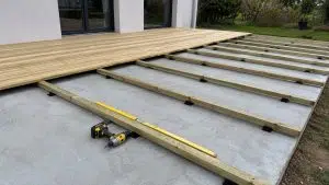 Aménagements de jardin en bois à monter soi-même 14 Chantier de pose d'une terrasse bois pin autoclave classe 4 sur dalle beton avec lambourdes fixees sur cales plastique noires, visseuse et niveau a bulle