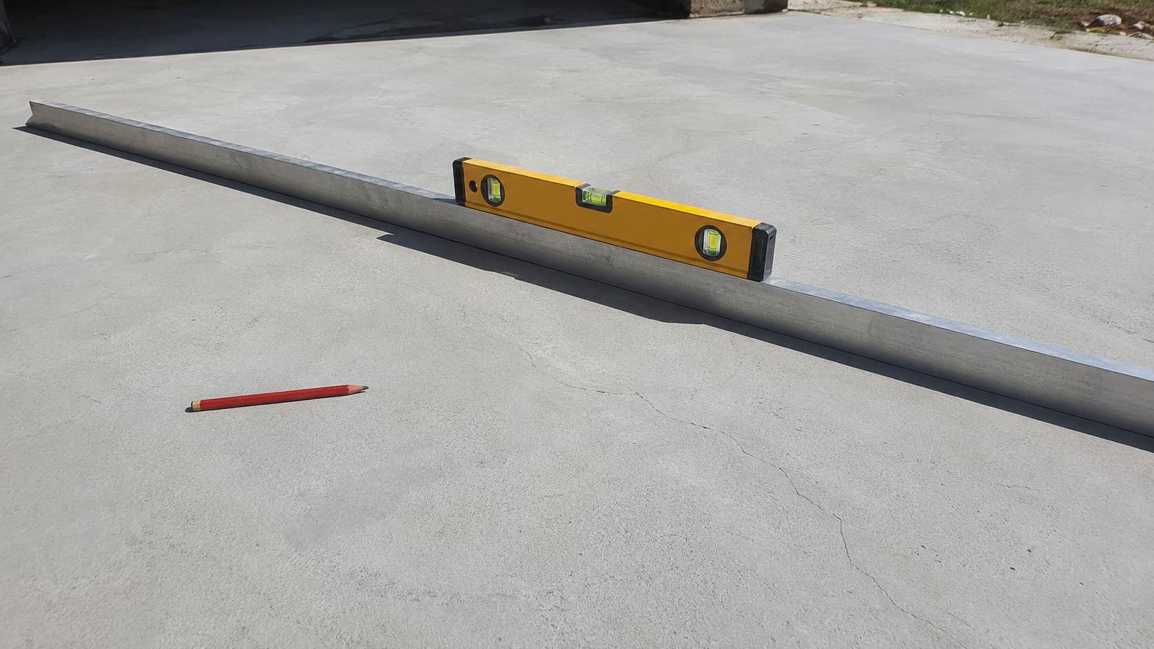 Terrasse bois sur dalle béton : préparation, pose, étanchéité (guide complet) 1 Controle de la planeite d une dalle beton avec regle alu 2 metres et niveau a bulle avant pose terrasse bois